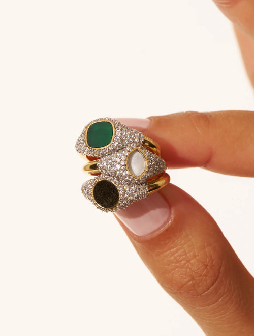 Multicolored gemstone ring on a finger against a white background
