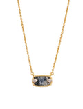 Gold necklace with a dark stone pendant on a light background