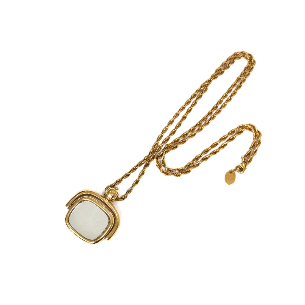 Gold necklace with a white pendant on a white background