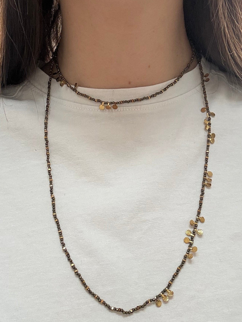 Person wearing a delicate necklace with small beads, close-up view.
