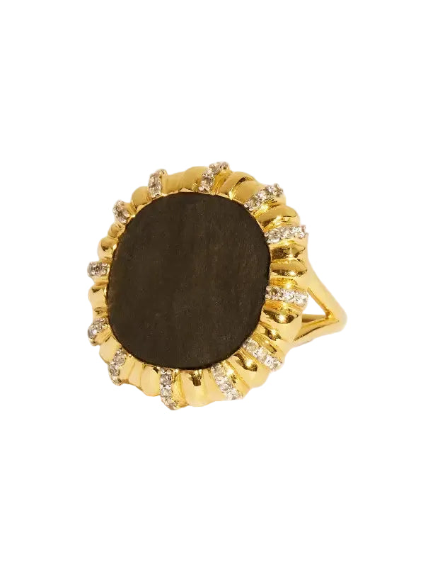 Gold ring with a dark stone and diamond accents on a beige background